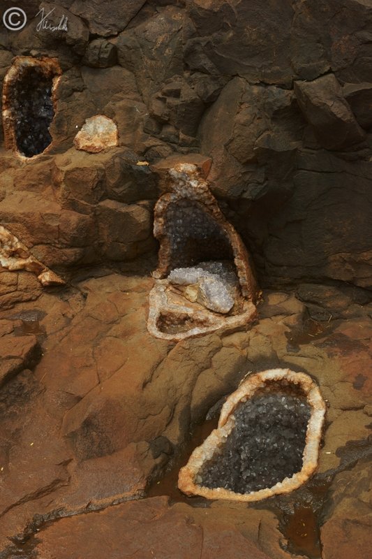 geöffnete Drusen mit Amethyst- und Quarz-Kristallen im Felsen